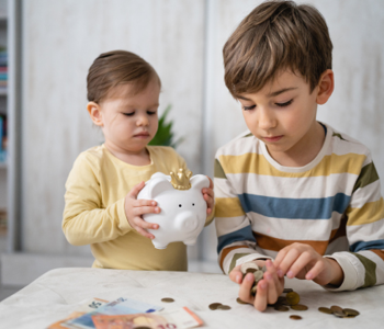 two kids putting coins into a piggy bank